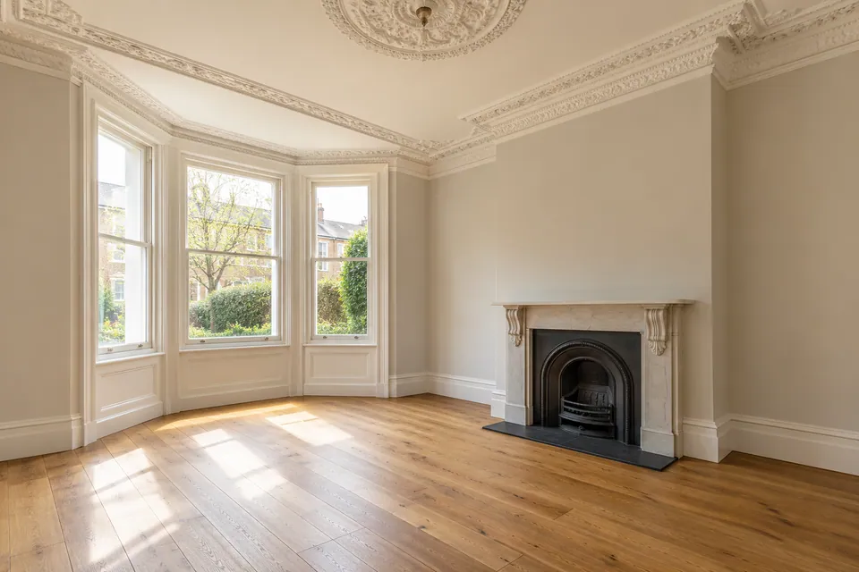 Empty period room with retained cornice and fireplace
